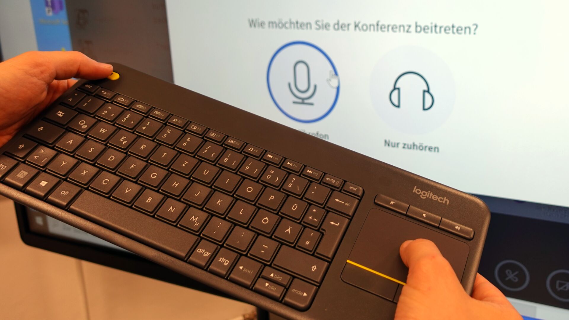 Die Funktatstatur wird in der Hand gehalten und Touchpad und Mausknopf werden bedient.